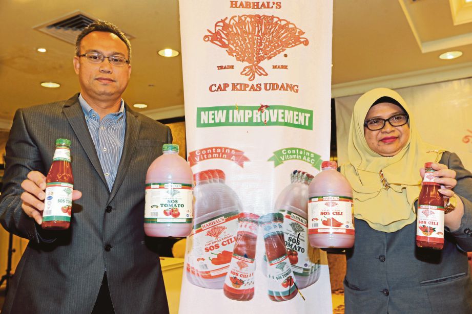 HASNAH bersama Mohd Nazri menunjukkan label baru produk sos cili dan tomato Cap Kipas Udang.