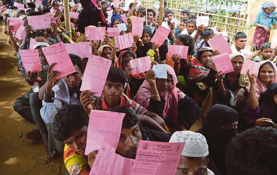 GAMBAR hiasan menunjukkan pelarian Rohingya memegang kupon masing-masing ketika menunggu mengambil makanan di kem pelarian Kutupalong, Ukhia, Bangladesh. - AFP  