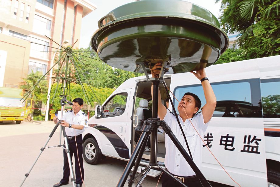 ANGGOTA kementerian pelajaran memasang sistem pengesan wayarles di luar sebuah sekolah tinggi di Xuchang di wilayah Henan, kelmarin.  - Reuters 