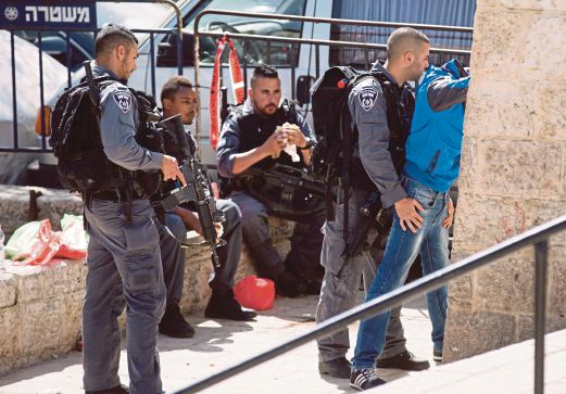 POLIS Israel memeriksa seorang remaja Palestin di Baitulmaqdis, semalam.