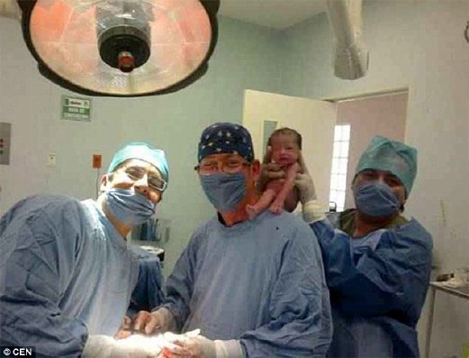 GAMBAR menunjukkan seorang doktor meletakkan bayi baru lahir  di atas bahu rakannya.