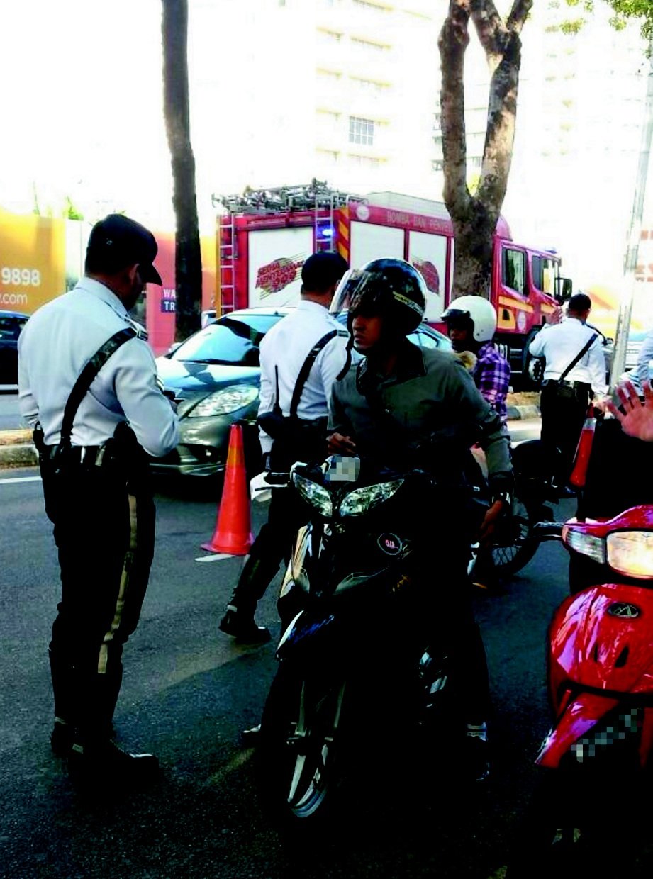 ANGGOTA polis trafik memeriksa penunggang motosikal.