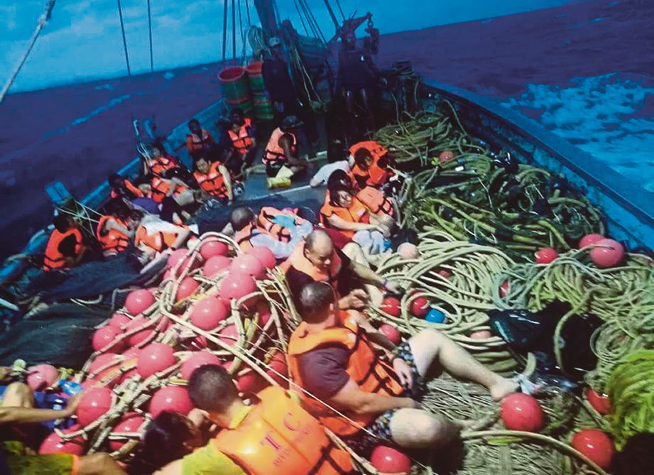 GAMBAR oleh Jabatan Marin Thailand menunjukkan mangsa bot karam di atas bot nelayan selepas diselamatkan. - Foto via EPA