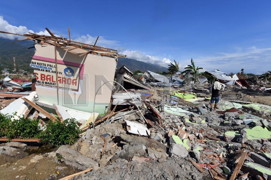 SEBAHAGIAN tembok sekolah yang dihanyutkan tanah cair kelihatan antara puing dan runtuhan di Balaroa. - AFP