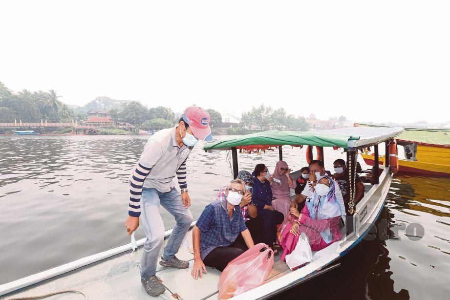  PENUMPANG perahu tambang turut memakai topeng hidung dan mulut berikutan kualiti udara tidak sihat di Sungai Sarawak.