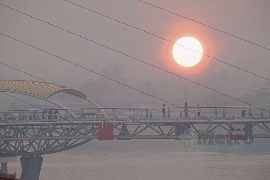 MATAHARI kelihatan berwarna kemerahan akibat jerebu yang dirakam berhampiran Jambatan Darul Hana di Tebingan Sungai Kuching, semalam.