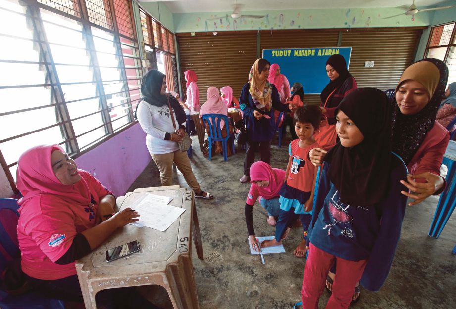 AHLI  Puteri UMNO mengukur saiz badan pelajar ketika Majlis Program Ziarah Kasih Happy 2 School anjuran UMNO Bahagian Kuantan di SMK Tanah Putih. 