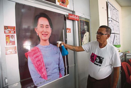 SEORANG pekerja membersihkan potret Suu Kyi di ibu pejabat NLD di Yangon, semalam.