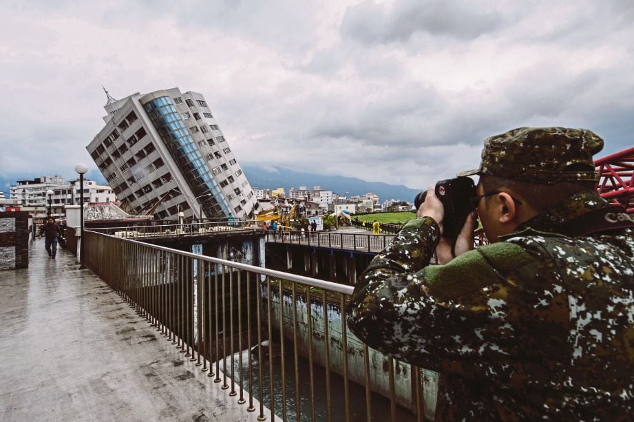 ANGGOTA penyelamat mengambil gambar bangunan Yun Tsui yang condong teruk akibat gempa, di mana 10 lagi mangsa hilang dipercayai berada di situ. - AFP 