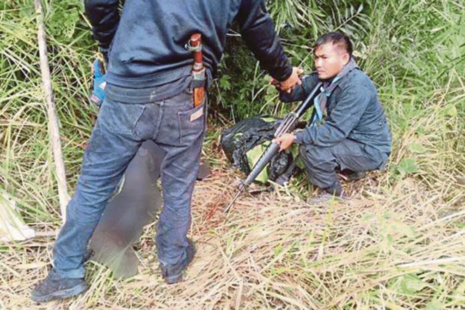 ASKAR Thai memeriksa mayat seorang penyeludup dadah yang ditembak mati di sempadan negara itu. - Bangkokpost