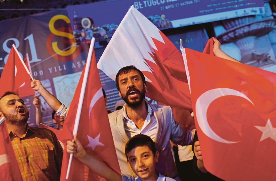 ORANG ramai melaungkan slogan sambil mengibarkan bendera Turki dan Qatar ketika menunjuk perasan menyokong Qatar di Istanbul, Turki, semalam.  - Reuters 