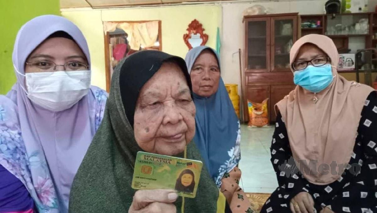 Umi Kastawi menunjukkan kad pengenalannya yang berusia 107 bersama anak cucunya. FOTO Ahmad Ismail