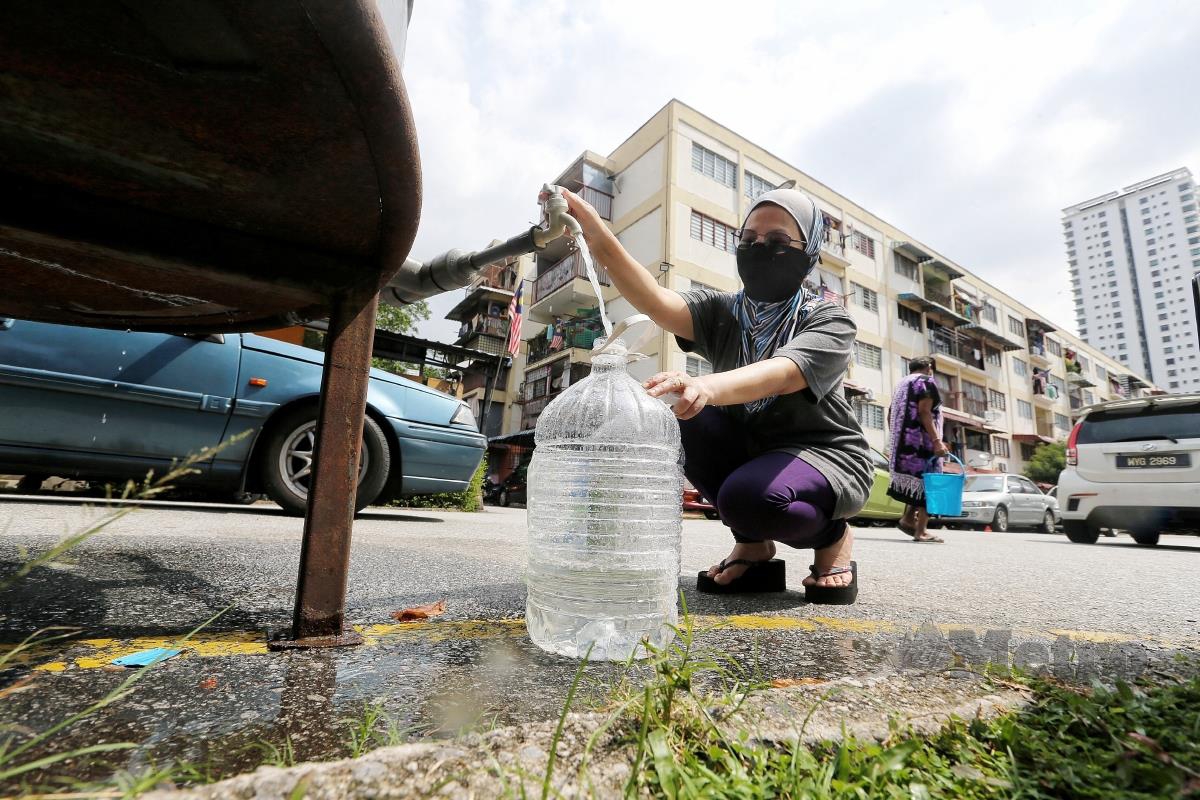Penduduk Perumahan Awam Seri Negeri Sembilan, Suriyati Son'an, 45, mengangkat air dari tangki Air Selangor Sdn Bhd yang diletakkan di tempat letak kereta perumahan. FOTO SAIFULLIZAN TAMADI