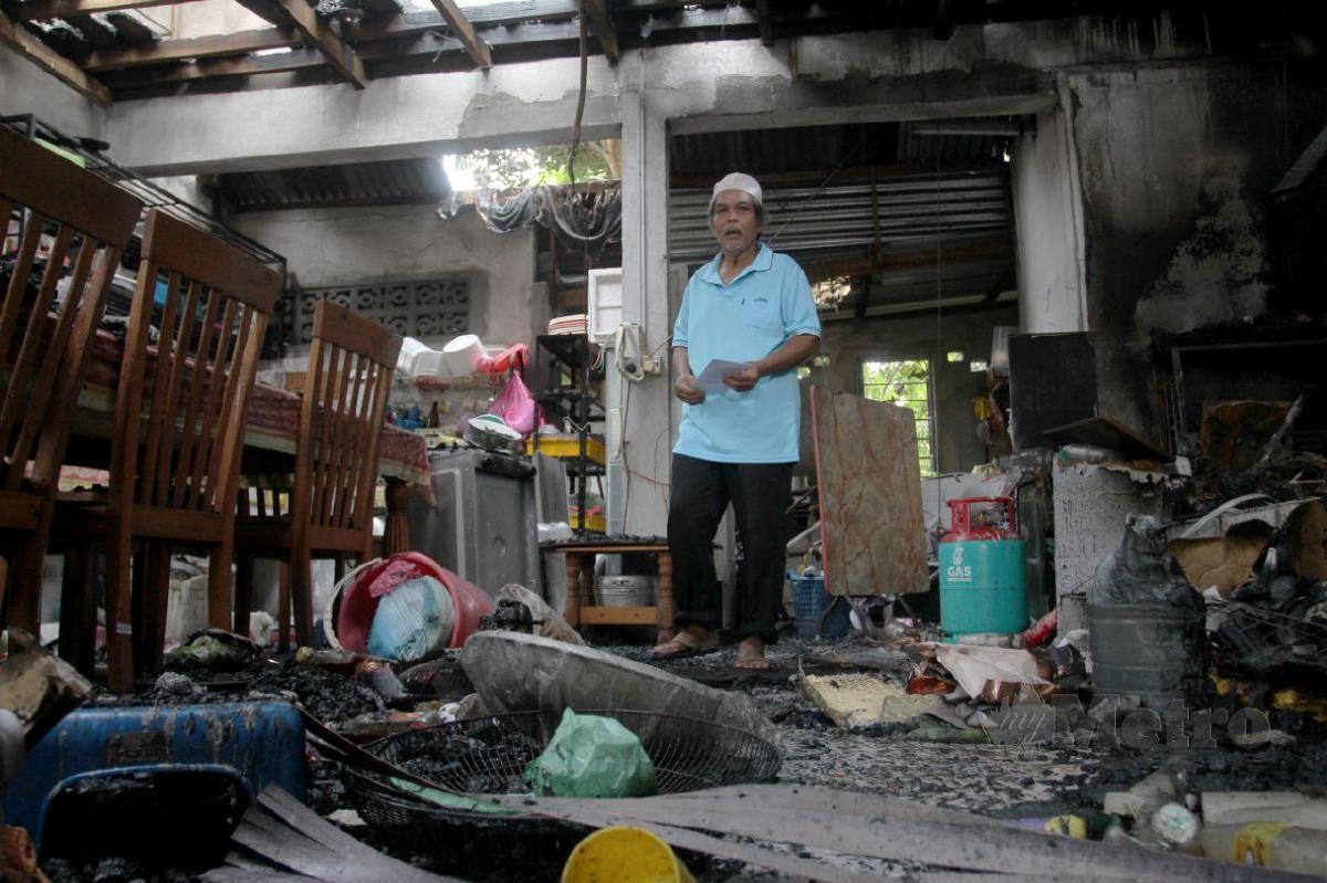 DOLLAH mencari saki baki barang yang musnah dalam kebakaran di Kampung Kok Pasir. FOTO NIK ABDULLAH NIK OMAR