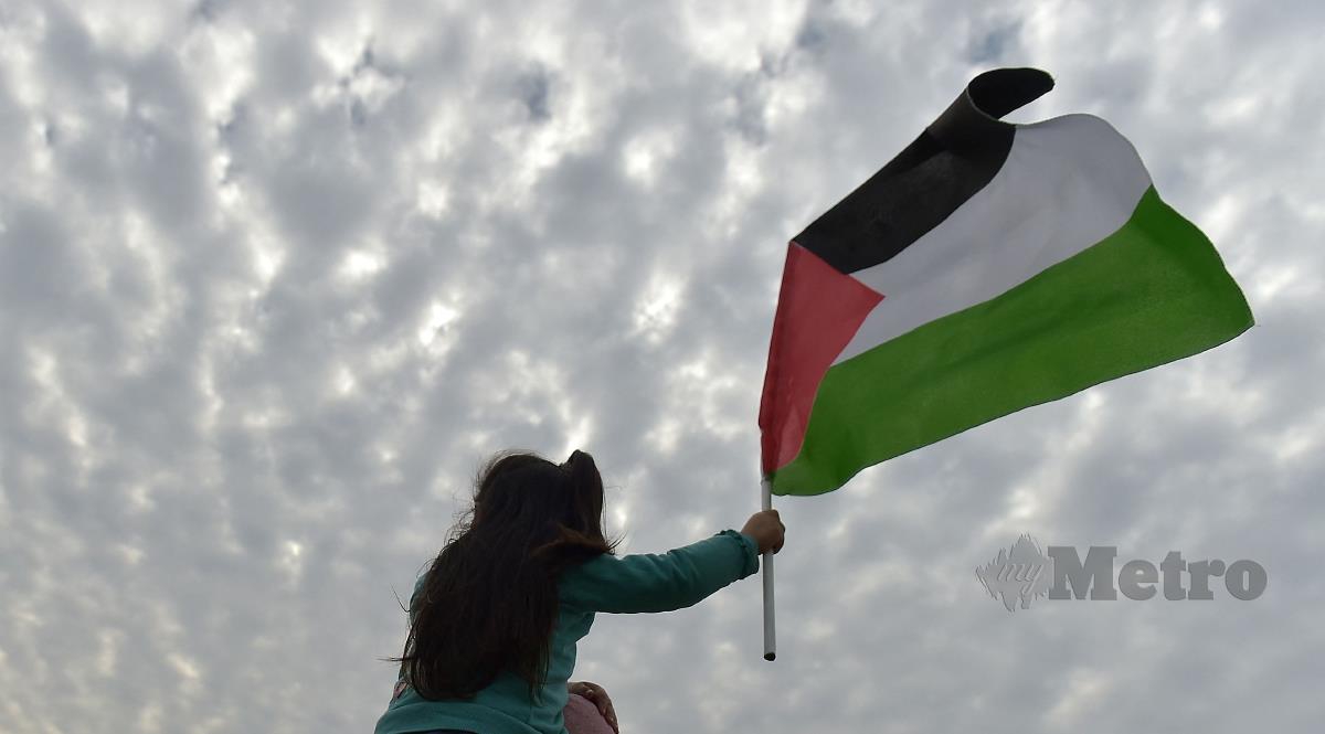 Kanak-kanak mengibar bendera Palestin. FOTO AFP