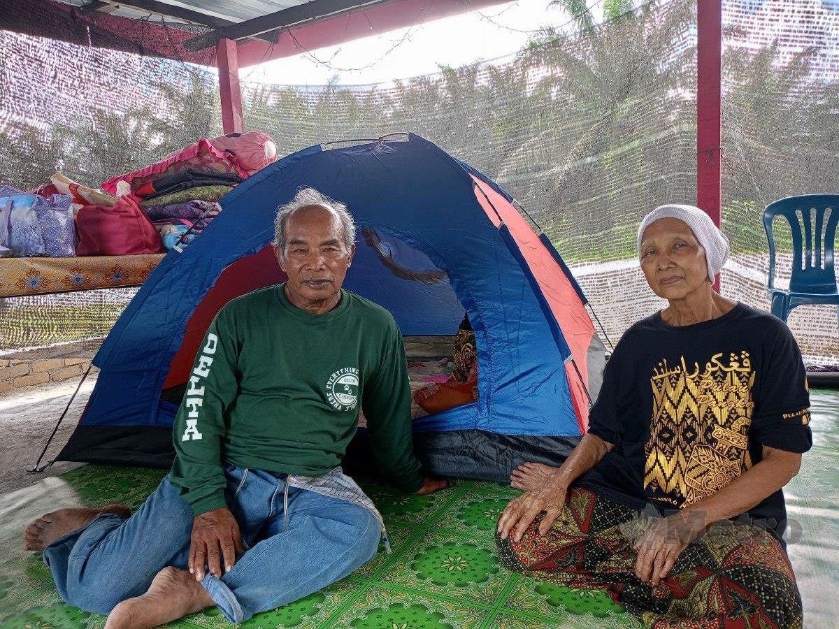 Abdul Mukti dan isteri, Saodah nekad berhujan berpanas dalam khemah di tepi Jalan Changkat Jong-Teluk Intan, bagi mengawasi rumah yang dimasuki air daripada geng pecah rumah. FOTO MUHAMAD LOKMAN KHAIRI.