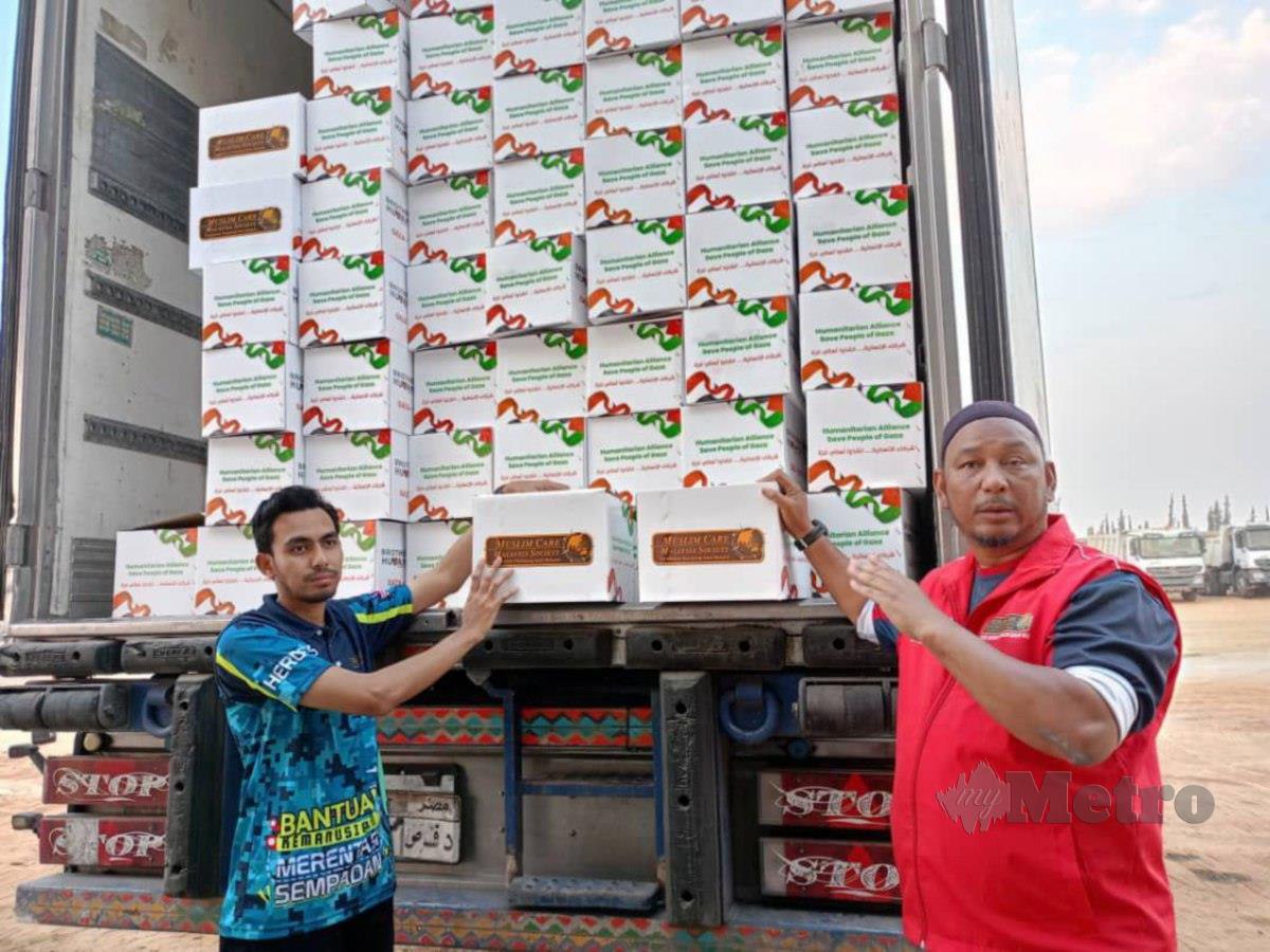 Mohd Johari (kanan) menunjukkan kotak berisi makanan yang dimuat naik ke dalam treler di Kaherah, Mesir untuk dihantar ke Gaza.
