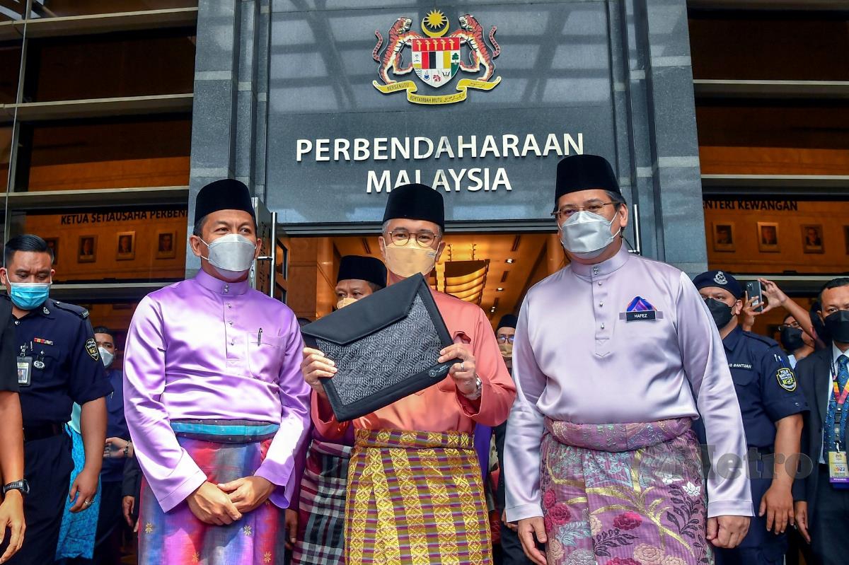 Menteri Kewangan Tengku Datuk Seri Zafrul Abdul Aziz (tengah) membawa laporan Bajet 2022 keluar dari Kompleks Kementerian Kewangan menuju ke Bangunan Parlimen bagi membentangkan bajet tersebut hari ini. FOTO BERNAMA