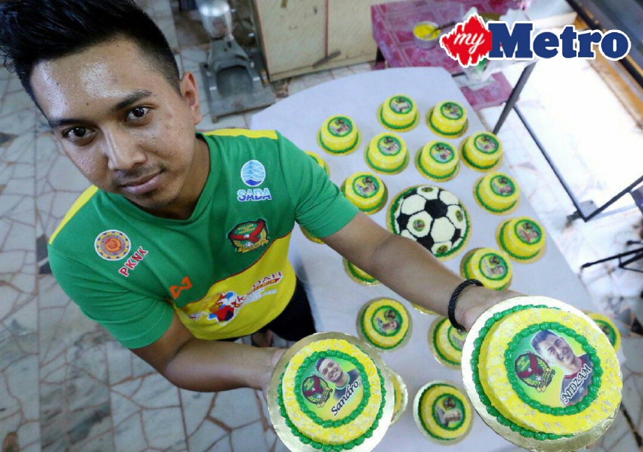 AZRUL Nizam Azali menunjukkan kek hijau kuning yang diletakkan dengan gambar pemain-pemain bola sepak pasukan Kedah sempena perlawanan akhir Piala Malaysia. FOTO Amran Hamid