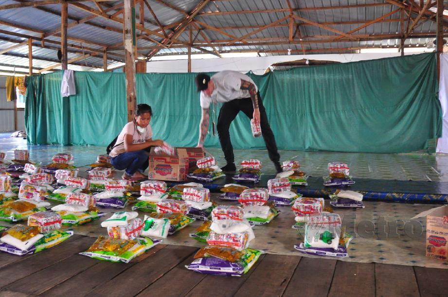 BENEDICT dan Lina menyusun sumbangan sebelum menyampaikannya  kepada penduduk Kampung Pondo, Pulau Gaya. FOTO Yun Mikail