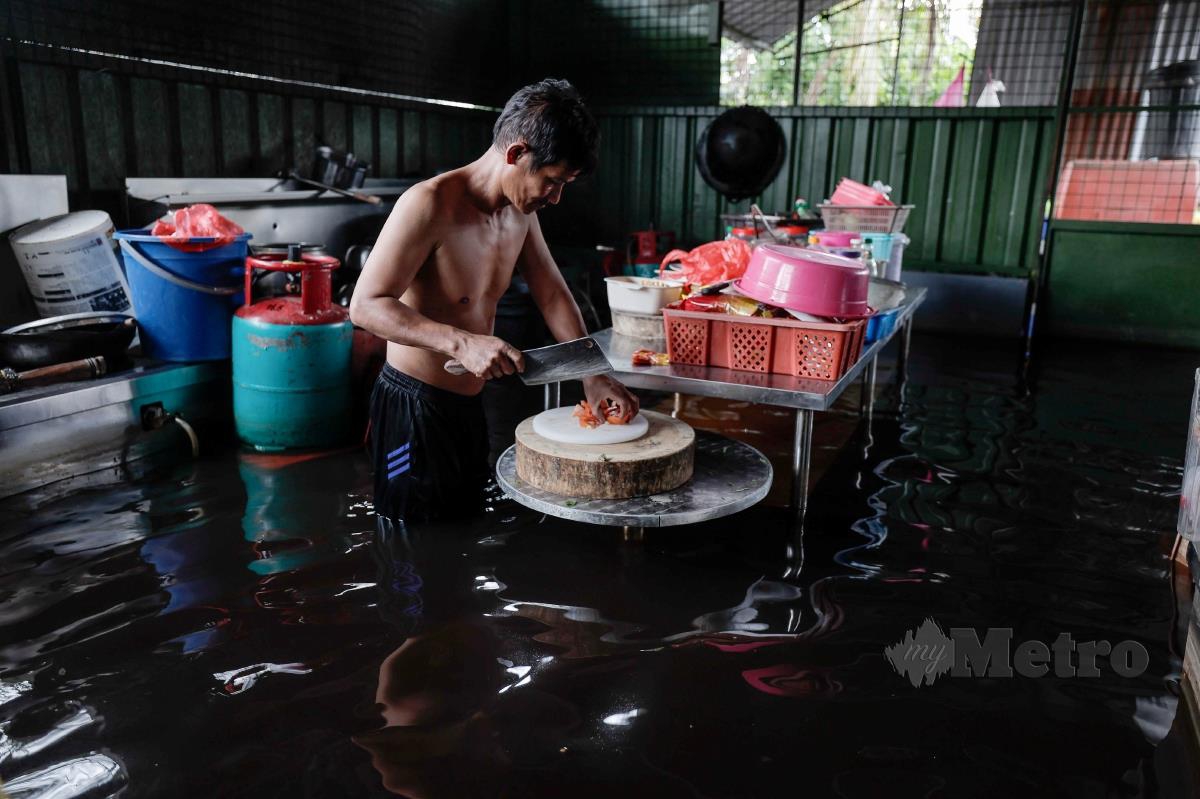 ENIAGA kedai makan, Rahim Ishak, 45, sibuk menyediakan bahan untuk dimasak ketika ditemui di kedainya yang digenangi banjir termenung di sekitar Parit Sulong, Batu Pahat, semalam.