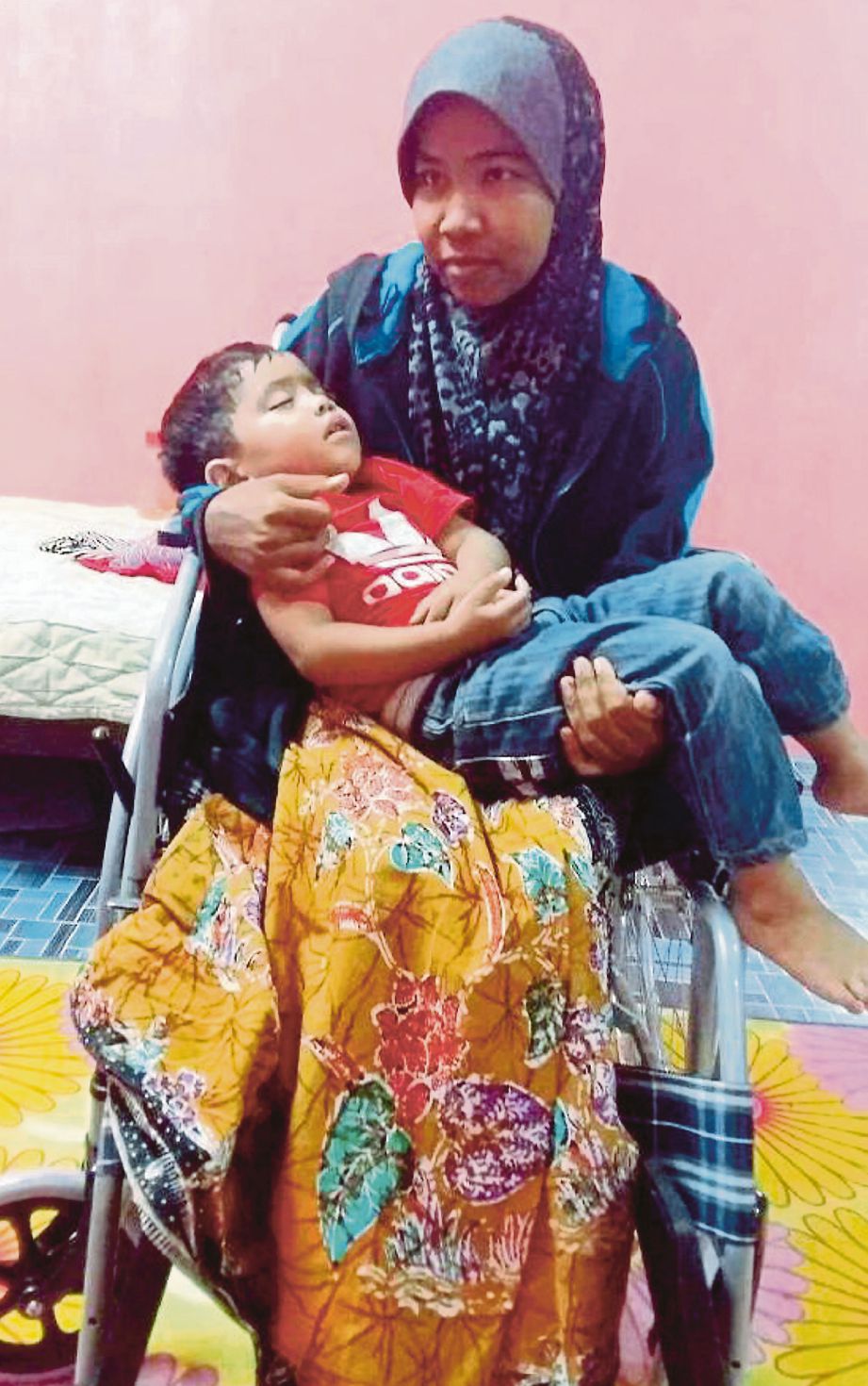 SUZANA   memangku anaknya, Adam Safiudin Ashraf, 3, ketika ditemui di rumahnya di Kampung To’Deh Barat.