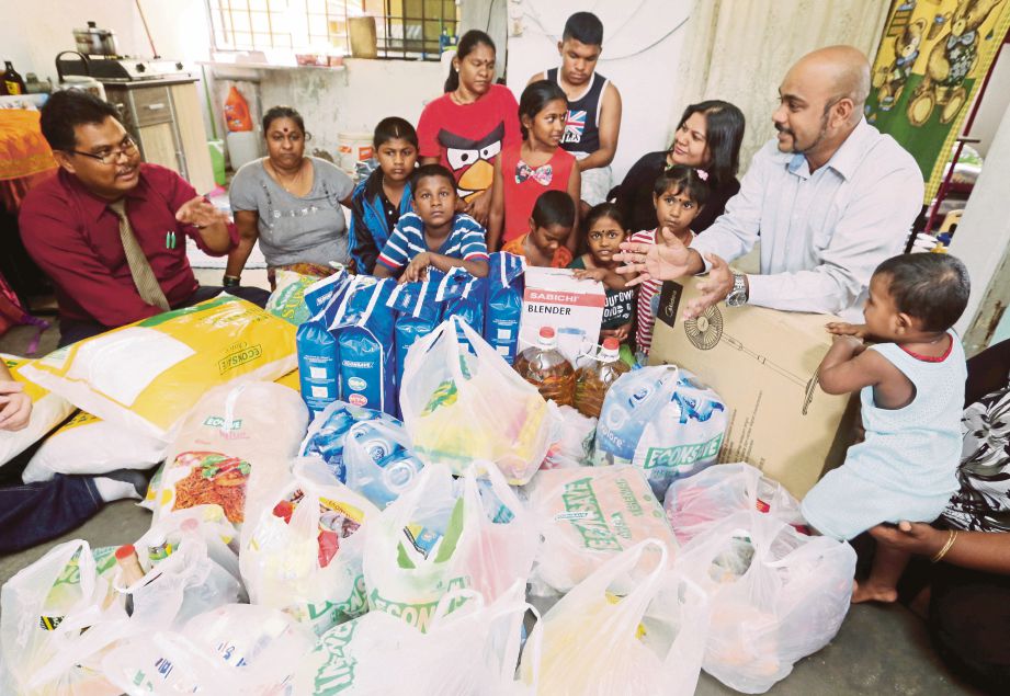 MAS Imran  (kiri) menyampaikan sumbangan barangan dapur dan keperluan kepada keluarga Magesvary sambil disaksikan sukarelawan D Murugan (kanan). 