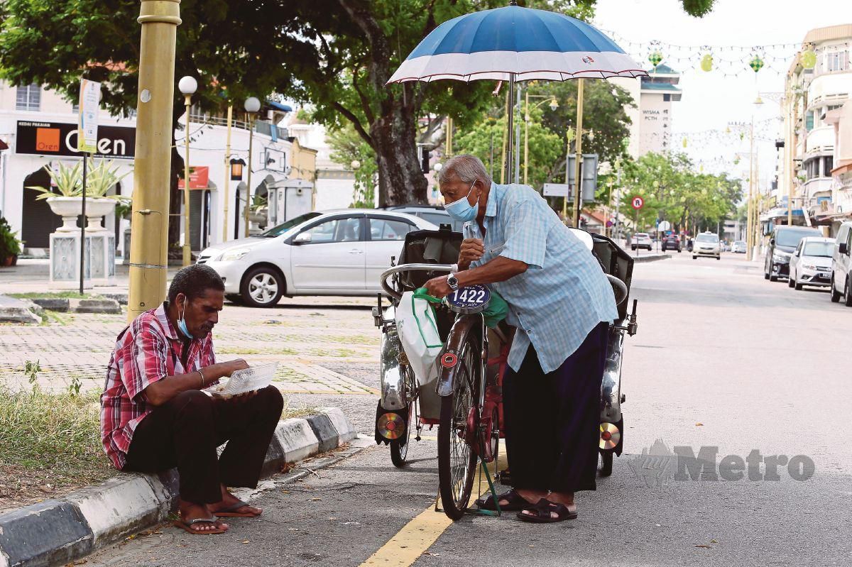 PENGAYUH beca menikmati makanan yang diberi Urban Life Volunteers di kaki lima jalan di Lebuh Armenian, Pulau Pinang.