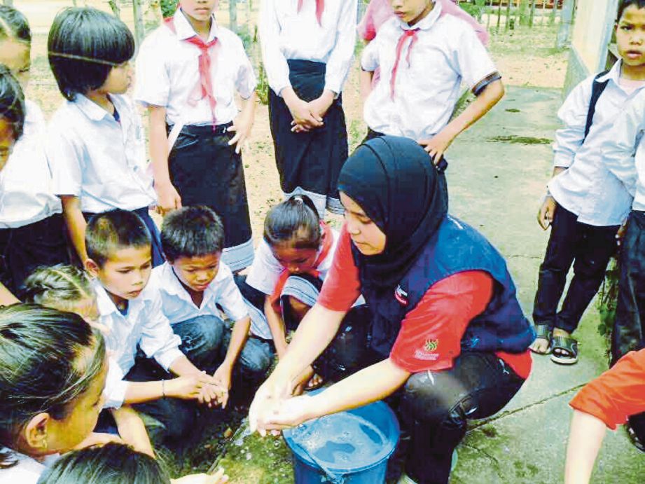 SITI Zurianah menunjukkan cara membasuh tangan dengan betul kepada kanak-kanak pada aktiviti tugasan sukarelawan.