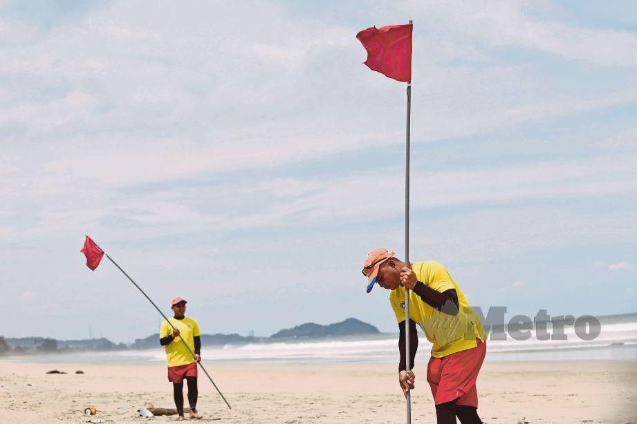ANGGOTA APM memacak bendera merah di persisiran Pantai Pulau Kekabu, Marang, semalam. 