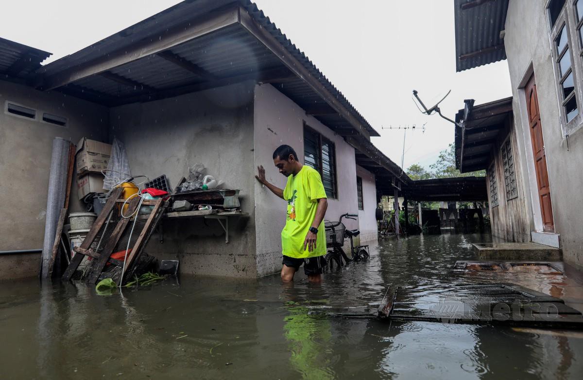 MOHD Shahrul Nizam Ab Rahman, 34, berjalan meredah banjir di rumahnya di Kampung Titian Baru. FOTO Ghazali Kori.