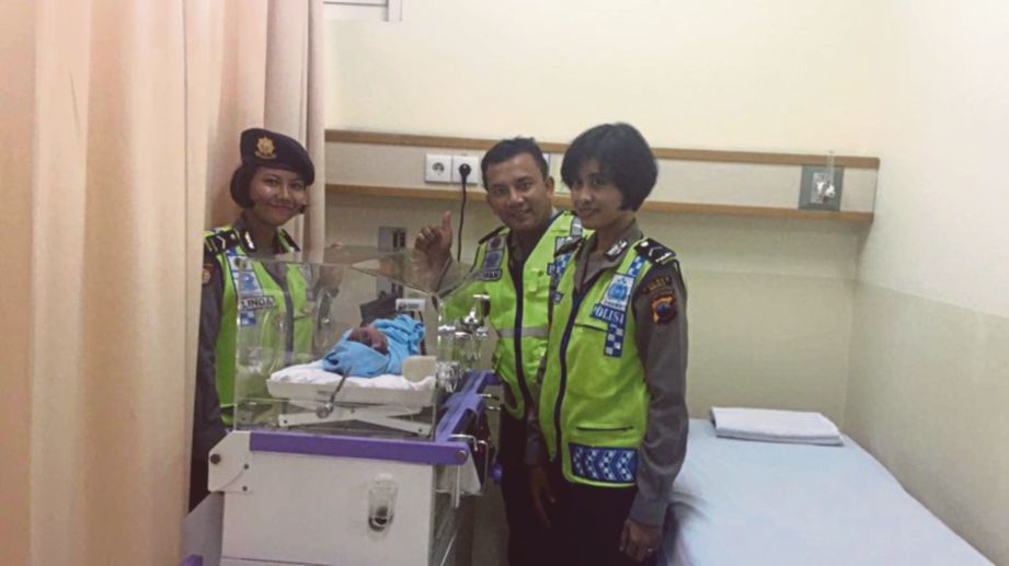 ANGGOTA polis bergambar dengan bayi yang dilahirkan seorang wanita di dalam sebuah bas di Brebes, Indonesia semalam. - Detiknews
