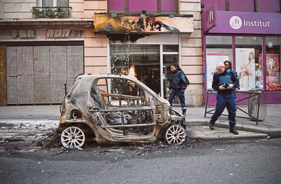 POLIS melihat  kereta yang terbakar di Beaubourg, Paris semalam selepas rusuhan jaket kuning terburuk di bandar itu. - AFP