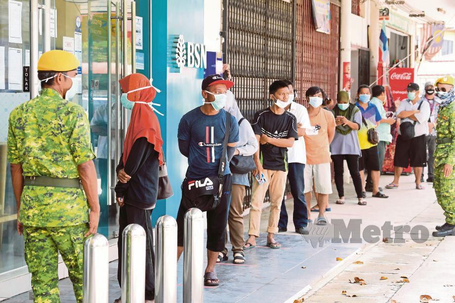 ANGGOTA Jabatan Sukarelawan Malaysia (Rela)  memastikan orang ramai mematuhi penjarakan sosial satu meter antara sama lain bagi menangani Covid-19 ketika berurusan di bank di bandar Beluran. FOTO Bernama 