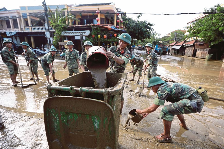 ASKAR membersihkan jalan yang berlumpur selepas banjir surut di Hoi An,  Vietnam semalam. - EPA