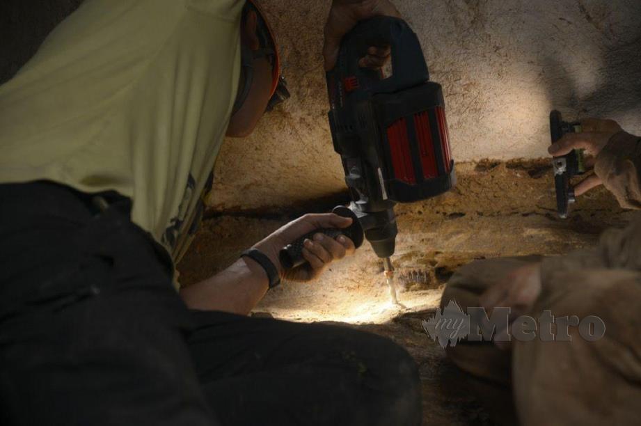 PROSES mengeluarkan fosil  gigi Stegodon daripada dinding gua. FOTO  IHSAN UM