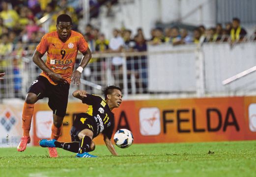 PEMAIN import FELDA United Makeche Ndumba (kiri) mengasak pemain Perak Muhammad Ridzuan Azly.  