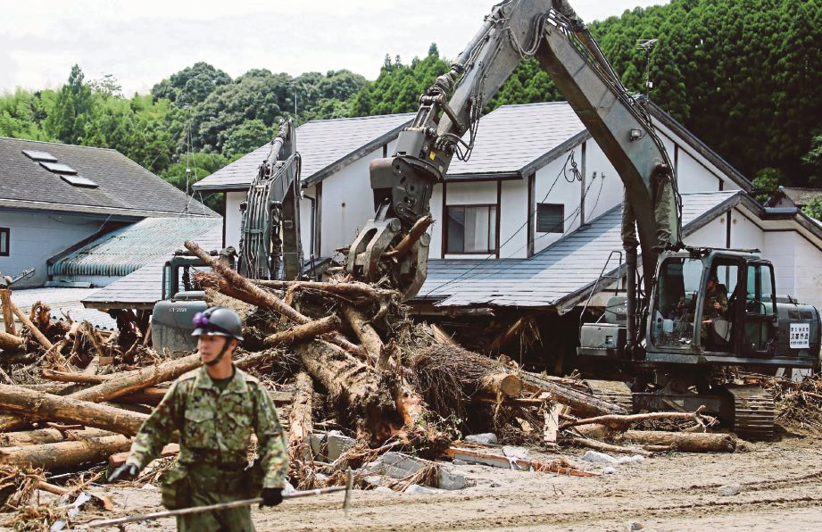 TENTERA membantu kerja pembersihan di kawasan banjir di Asakura di wilayah Fukuoka, semalam.  - AFP