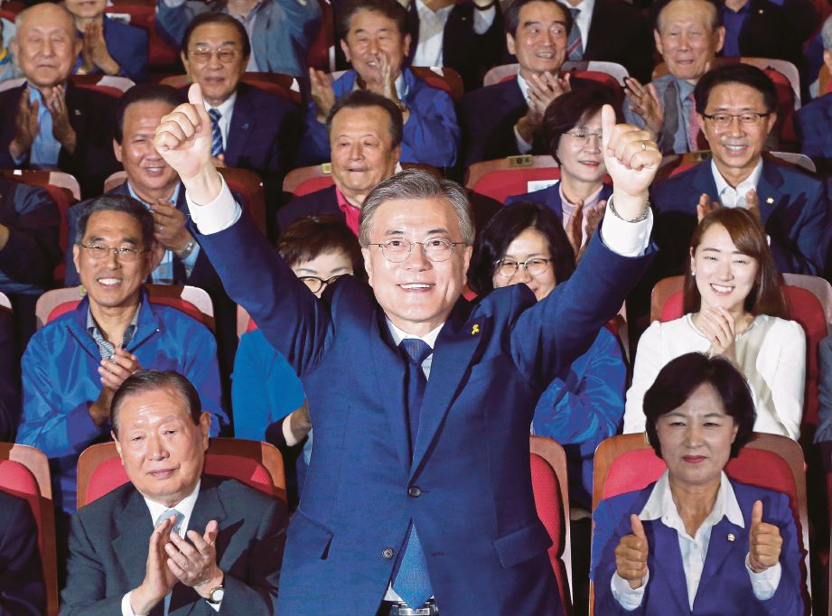 MOON Jae-in mengangkat tangannya selepas kiraan awal menunjukkan dia memenangi pilihan raya Presiden Korea Selatan, di Seoul,  semalam. - AP