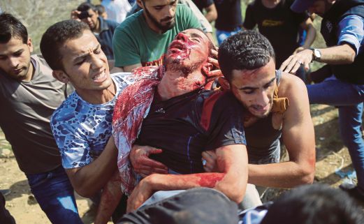 SEORANG penunjuk perasaan Palestin dibantu rakannya selepas cedera dalam pertempuran dengan tentera Israel di pagar sempadan di Semenanjung Gaza, semalam. 
