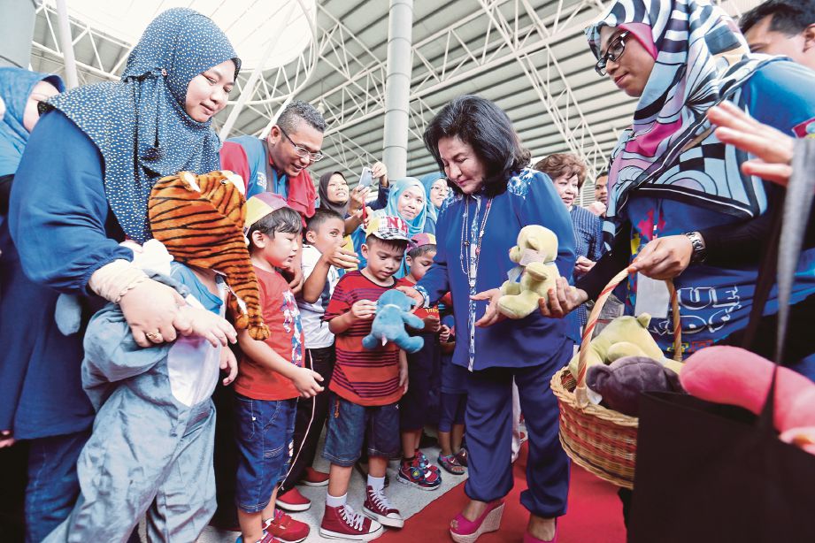 Rosmah  menyampaikan cenderahati kepada kanak-kanak autisme ketika tiba di program Blue Kids Fun Zone sempena bulan kesedaran autisme di Pusat Kecemerlangan Sukan Paralimpik, Kampung Pandan.