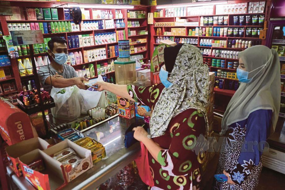 PENIAGA kedai runcit, Mahadzir M Hassan melayan pelanggan di kedainya di ibu kota.