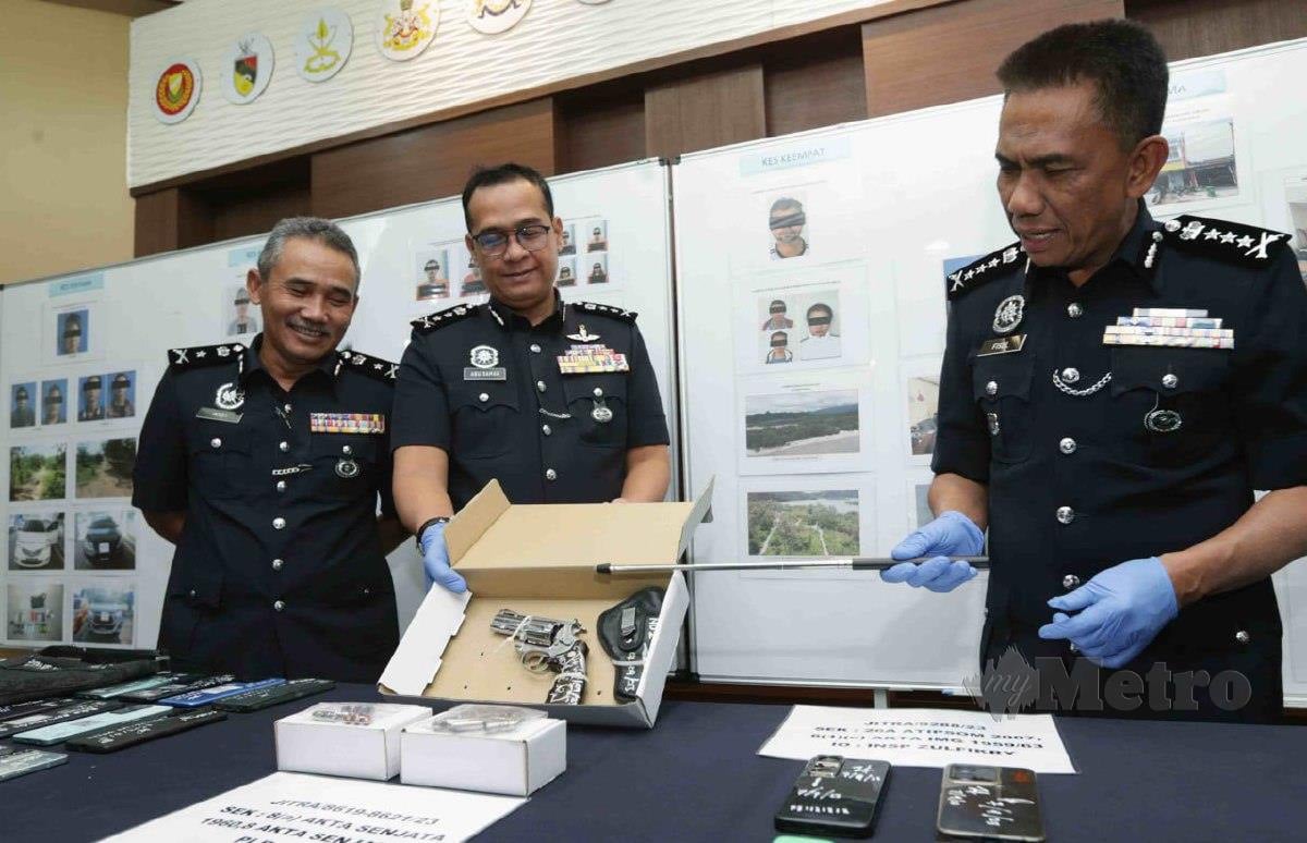 FISOL (kanan) menunjukkan pistol dan barangan lain yang dirampas susulan penahanan 12 ejen sindiket pemerdagangan manusia di Kedah. FOTO Syaharim Abidin.