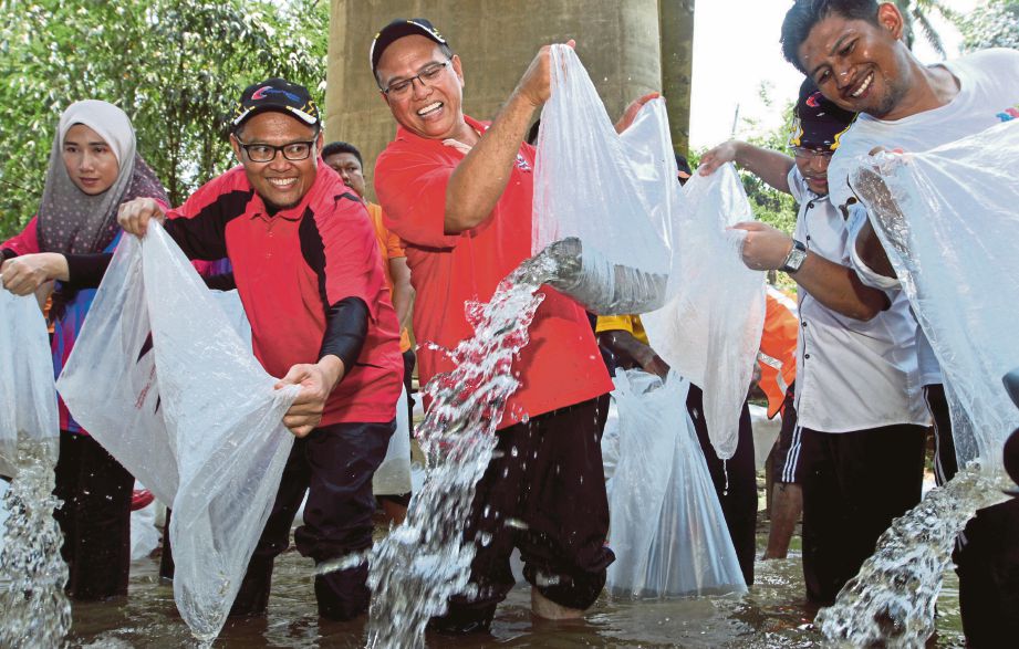 WAN  Rosdy   (kanan) dan  Adnan   (kiri) melepaskan benih ikan pada program   di Sungai Kuala Serau, kelmarin.