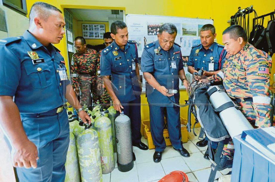 MOHD  Khairil Azamin  (kiri)   bersama   anggota Unit PPDA    memeriksa alat kelengkapan skuba di Balai Bomba dan Penyelamat Kota Bharu.