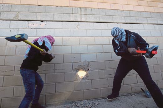  PEMUDA Palestin menggunakan tukul untuk memecahkan sebahagian daripada tembok konkrit yang dibina di Bir Nabala. 