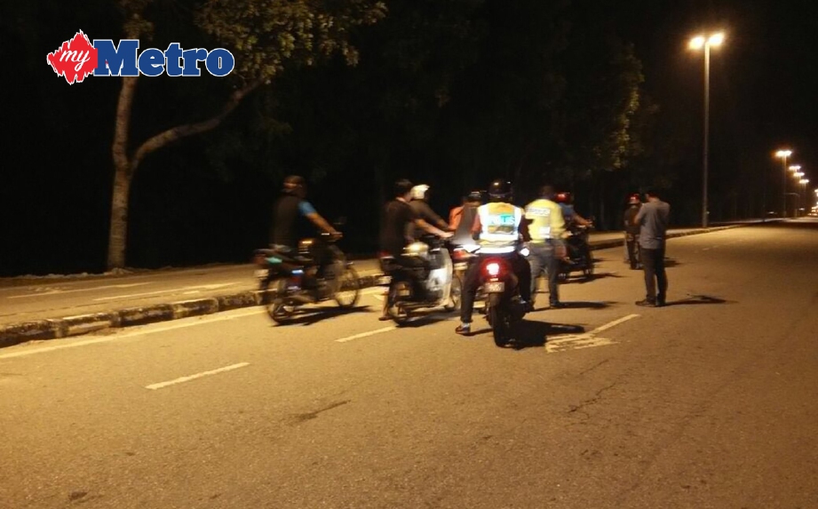 PENUNGGANG motosikal menolak motosikal selepas ditahan polis. FOTO Noor Hidayah Tanzizi
