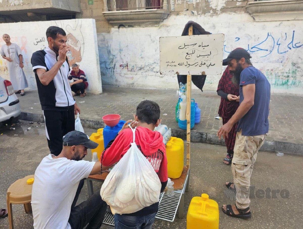 Seorang penduduk menawarkan air minuman percuma kepada orang ramai. FOTO FB Dr Ziad