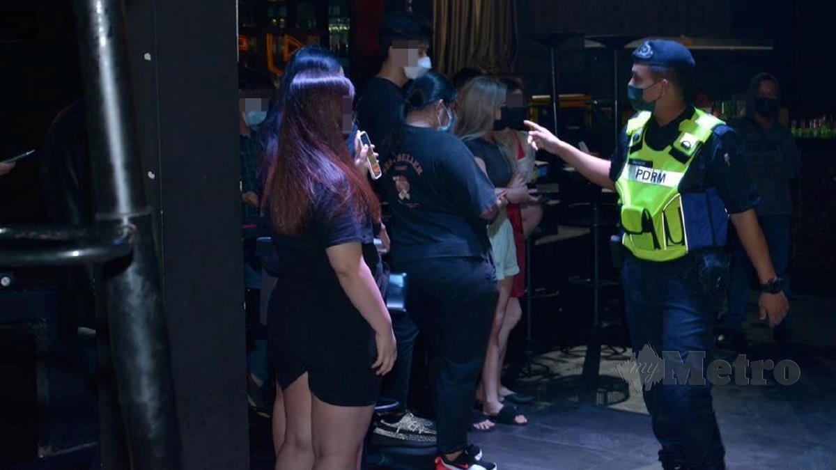 ANGGOTA polis menjalankan pemeriksaan ke atas pengunjung pusat hiburan. FOTO Juwan Riduan