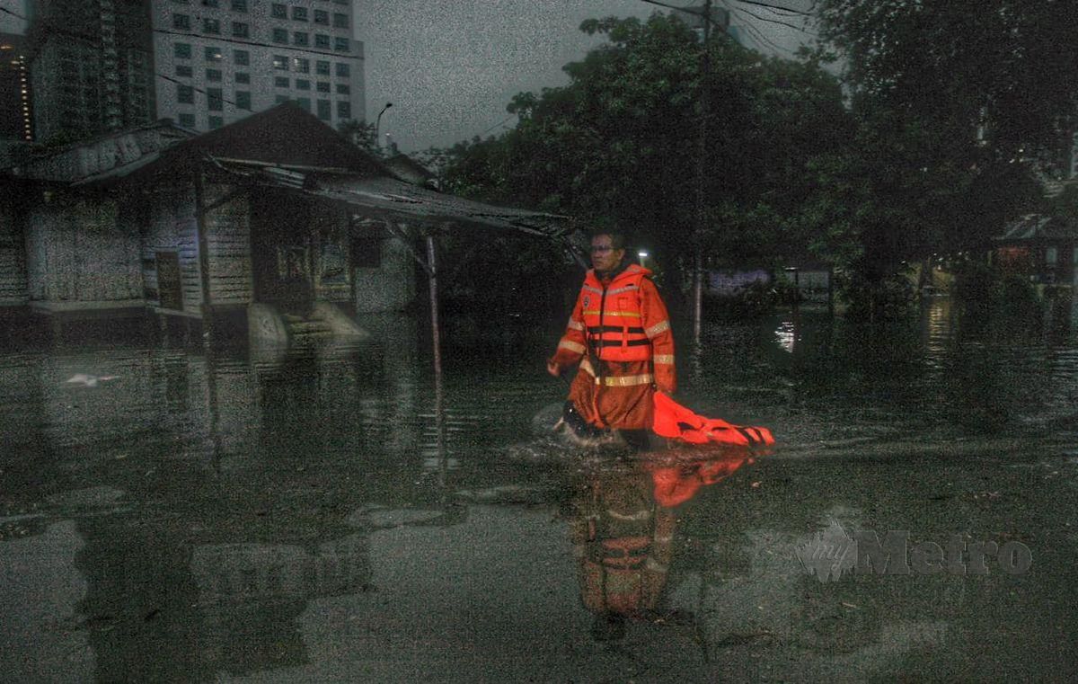 Anggota Angkatan Pertahanan Awam (APM) meredah banjir untuk memanggil keluar penduduk sekitar Kampung Periuk keluar dari kediaman mereka susulan kejadian banjir kilat di sekitar Kuala Lumpur. FOTO MOHD YUSNI ARIFFIN